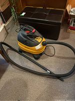 Full view of the Shop-Vac unit with hose coiled on floor shows overall condition and accessories included.