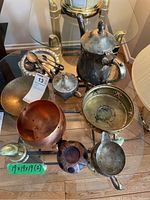 Top view of all items on glass table showing silver plated tea set pieces and large copper bowl.