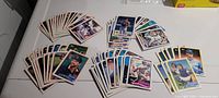 Photo showing multiple 1988 Topps MLB baseball cards laid out on a white table, grouped by teams from the Atlantic League Central division.