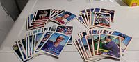 Multiple piles of 1988 Topps baseball cards on a white surface, featuring players from Blue Jays, Yankees, Red Sox, and Orioles.