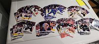 Photo showing an assortment of 70+ 2022-2023 NHL Upper Deck Series 1 hockey cards from the Pacific Division teams spread on a white surface.
