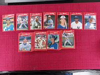 Eleven Donruss 1990 baseball cards displayed on a red surface, each in protective sleeves showing different players.