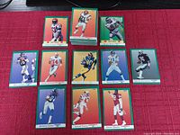 Photo showing eleven different Fleer 1991 football cards arranged on a red cloth, displaying each player's image and name.