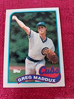 Front image of a Greg Maddux baseball card in Chicago Cubs uniform from Topps showing the player pitching with a striped jersey.