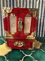 Front view of the rectangular wooden box with double doors featuring carved jade panels and brass hardware.