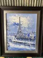 Full view of the framed painting showing the Eiffel Tower and cityscape in blue and white tones.