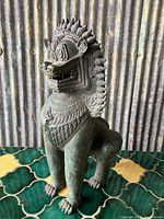 Full view of the metal Foo Dog statue showing textured patterned surface and pose.