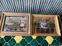 Two vintage advertising mirrors side by side on a surface showing Coca Cola and Coach & Horses designs in wooden frames.