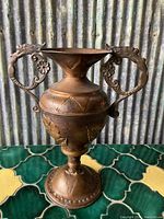 Full view of the vintage copper vase showing its shape, base, and figural handles.