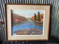 Full view of framed original landscape painting showing river, autumn foliage, and rock formation under glass.