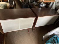 Pair of vintage mid century modern stereo speakers showing wood finish and fabric front.