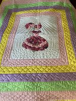 Photo showing entire quilt with central figure and multicolored pastel borders