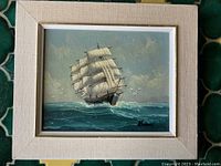 Full view of the framed ship painting on canvas showing the ship on the ocean with sails fully extended and a partly cloudy sky.