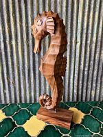 Front view of the wood carved seahorse figure showing detailed ridges, eyes, fins, and wooden base.