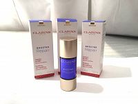 Three boxed and one unpackaged bottles of Clarins Booster Repair serum with front labels.