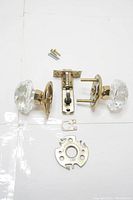 Full set of door handle, latch mechanism, and mounting hardware laid out on white surface.