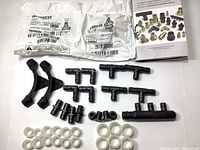 Image showing black plastic plumbing fittings including elbows, tees, plugs, straight connectors, white support rings, two sealed bags containing valves, and a manual for Uponor Propex parts.