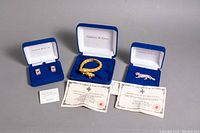 Full view of the jewelry set showing hinged cuff bangle, earrings, pink panther brooch, original blue velvet boxes, Certificates of Authenticity, and signature card.