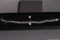 Full view of the silver tennis bracelet with CZ stones and one stud earring inside a black box.