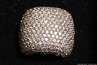 Top view of a broad sterling silver cocktail ring densely set with small clear cubic zirconia stones, highlighting the sparkling surface.