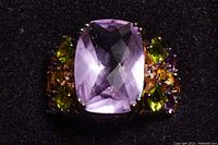 Close-up top view of the ring showing the large purple cushion-cut center stone with surrounding multicolored crystals.
