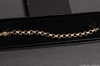 Full view of the gold-toned bracelet on black velvet inside a black box.