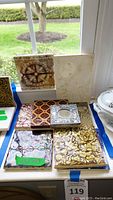 Overall view of nine decorative ceramic tiles arranged on table by window