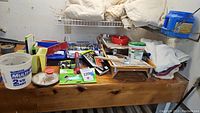 Wide view of painting supplies on wood surface showing multiple items including painting pads, trays, and tarps.