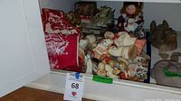 Wide view of the assorted vintage Christmas decorations including figurines, a red stocking, and other holiday items laid out in a box.