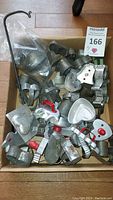 Box filled with assorted vintage metal cookie cutters of various shapes and sizes including hearts and stars.