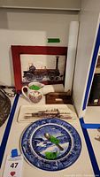 Photo of the ceramic railroad pitcher, two plates (rectangular train tray and blue-white scenic plate), wooden railroad stake and framed vintage train prints