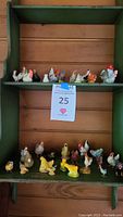 Photo of two shelves displaying a total of 26 miniature rooster and chicken figurines, various colors and sizes, arranged in rows