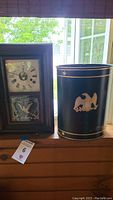 Vintage Seth Thomas mantle clock next to black metal trashcan with eagle design.