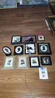 Overview of all 10 framed silhouettes and paintings on wooden floor