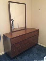 Front view of walnut-tone mid century modern dresser with attached rectangular mirror, showing six drawers and finish
