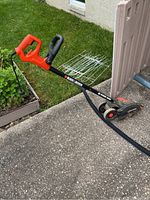 Full view of the red and black Black & Decker Edge Hog electric lawn edger showing handle, wheels, and cutting head.