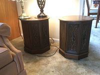 Pair of matching drum end tables placed near a couch. Wooden with dark finish, round tops, and hexagonal bases.