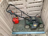 Black & Decker MM1450 mulching lawnmower with red fuel container inside plastic storage bin.