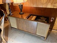 Front view of the wooden cabinet showing the speaker grills and lamps on top.