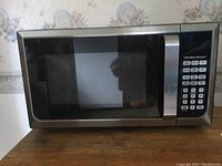 Hamilton Beach microwave oven front view showing closed door, stainless steel with digital keypad control panel on right side