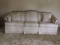 Front view of the floral upholstered sofa showing cushions and skirted base.