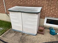 Front view of beige and gray Rubbermaid plastic storage box, showing double front doors and curved top with lock latch.