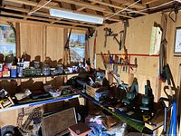 Wide view of basement tool storage with shelves containing cans, containers of hardware, and hand tools hung on wall.