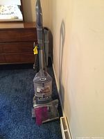 Full view of Shark Navigator NV351 vacuum cleaner upright on carpet, includes attached hose and power cord, with booklet and attachments in front