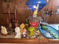 Photo of vintage bar decor items including Miller Lite metal beer bucket sign, carved wood candlesticks, figurines, and San Francisco themed tray with metal letters.