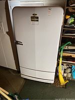 Full frontal view of the white vintage refrigerator showing door and base.