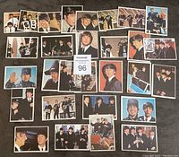 Photo showing 29 assorted 1964 Beatles color trading cards laid out on a dark surface with photo tag in center.