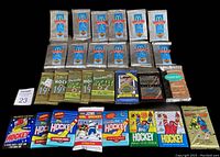 Lot showing 28 unopened hockey card packs arrayed on a black background. The packs include McDonalds 1991 (12 packs), several OPC packs, Bowman, Score, and Topps. The packaging is mostly silver foil and colorful printed wrappers.