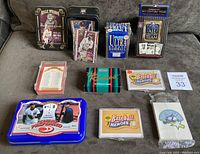 Photo showing all nine baseball card sets including factory box sets, sealed packs, and tins displayed on a couch.