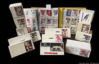 Photo of opened binders and multiple hockey card boxes stacked and displayed showing hockey card sets in plastic sleeves and card boxes with labels for series and years.